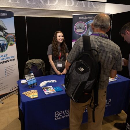Attendee interacting with exhibitor at a booth with blue branding.
