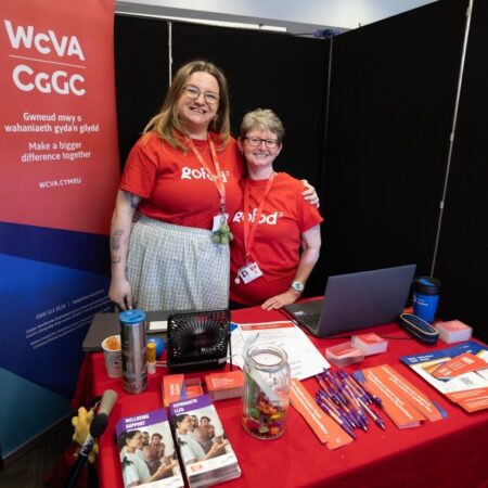 Exhibitors in red shirts standing near a booth with event signage.
