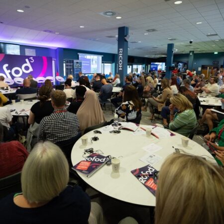 Large round tables filled with attendees listening to a speaker.
