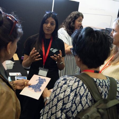 Attendee speaking to a small group, holding a clipboard.