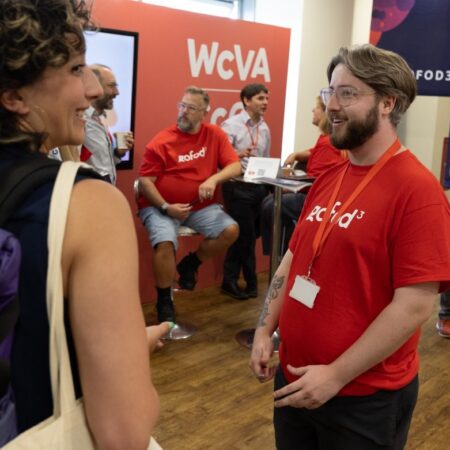Group discussion in progress, people wearing red “gofod3” t-shirts, one person with glasses and beard talking.