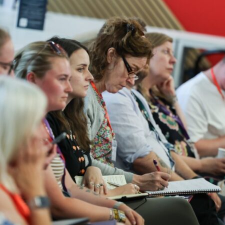Audience members sitting in rows, taking notes during a presentation.