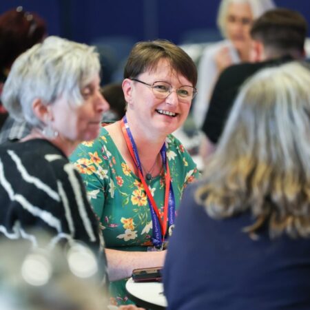 Three people in conversation, smiling during a networking session.
